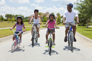 A Black African American family of two parents and two children, two girls, cycling together.